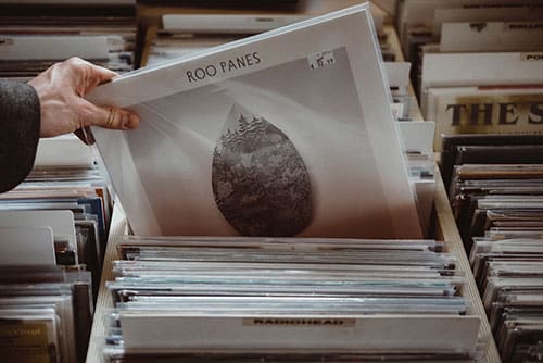 A person picking up a cd in a record store.