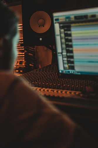 A man is working on a computer in a recording studio.