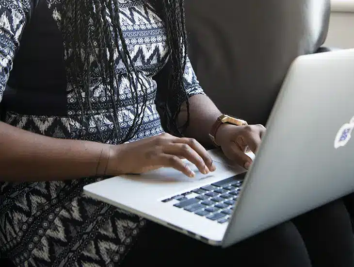 A woman engrossed in her laptop on a cozy couch, reading an important letter from Symphonic's CEO.