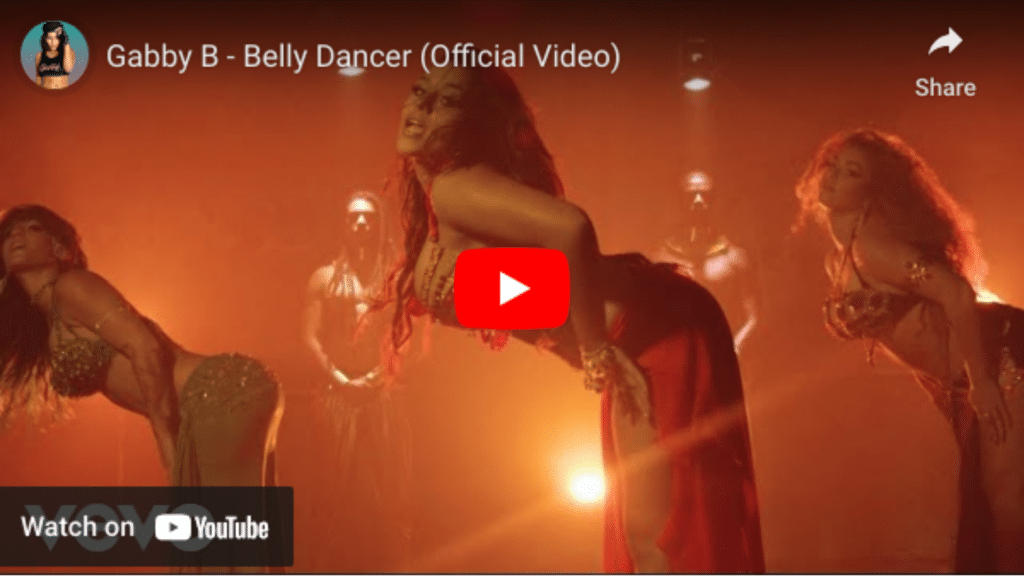 Three belly dancers performing in a dimly lit scene, the central dancer in focus, bending backward with dramatic expression. This performance is ideal for video distribution.